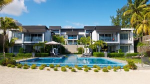 Exterior-modern-design-apartment-resort-Mauritius-front-yard-blue-water-swimming-pool-trees-palm-tile-floor-window-relaxing-chair-umbrella-stairs-ornamental-green-grasses-natural-stone-wall