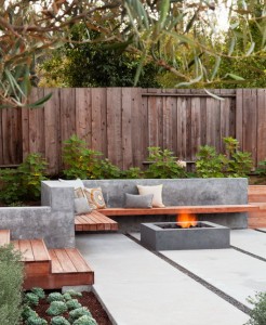 L-Shaped-Wooden-Seating-with-Concrete-back-and-Square-Fire-Pit-with-Rock-Fire-Glass-in-Modern-Patio-Design-Ideas